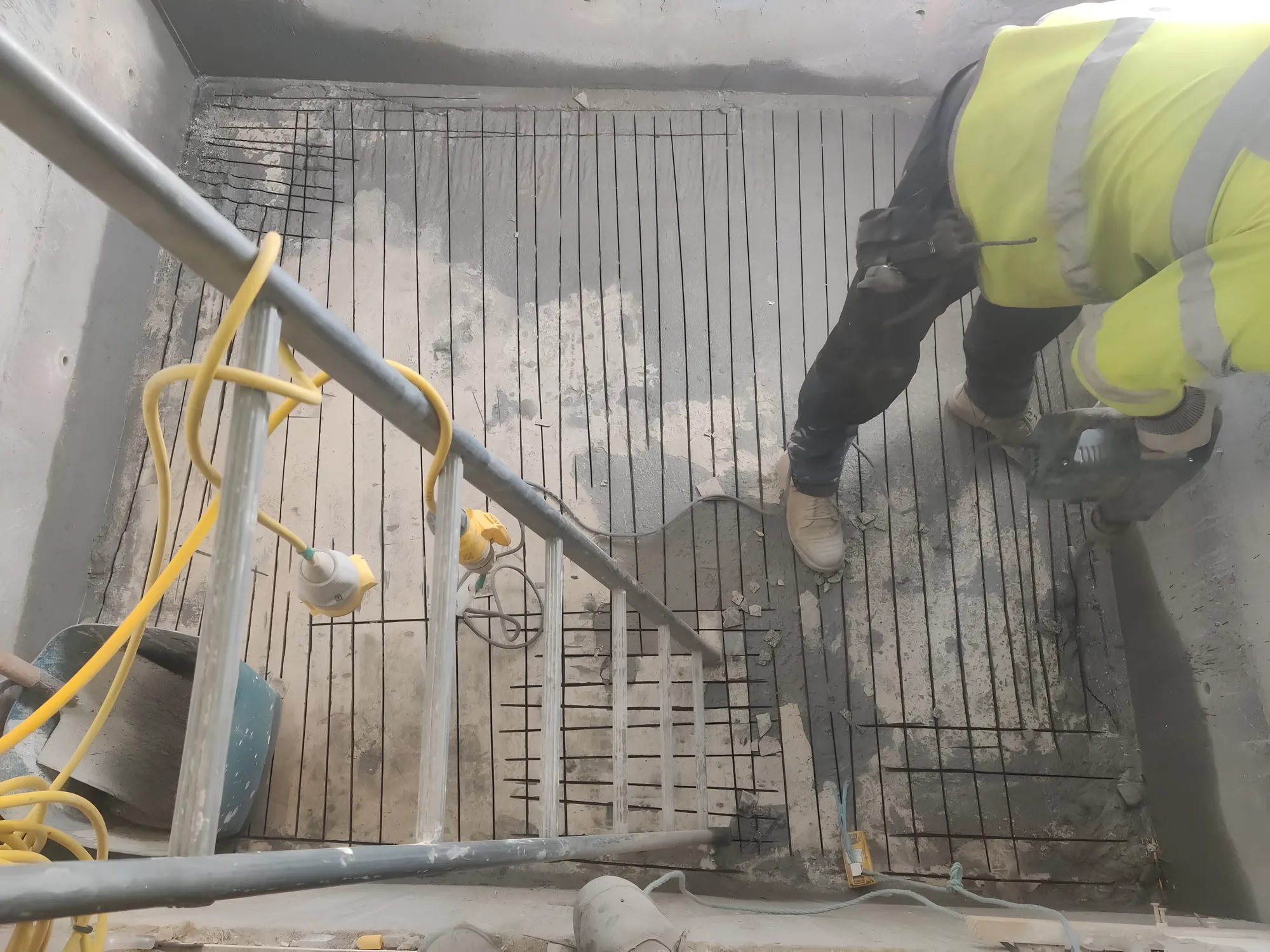 Operator in hi-vis breaking out a concrete slab down to the steel mesh.