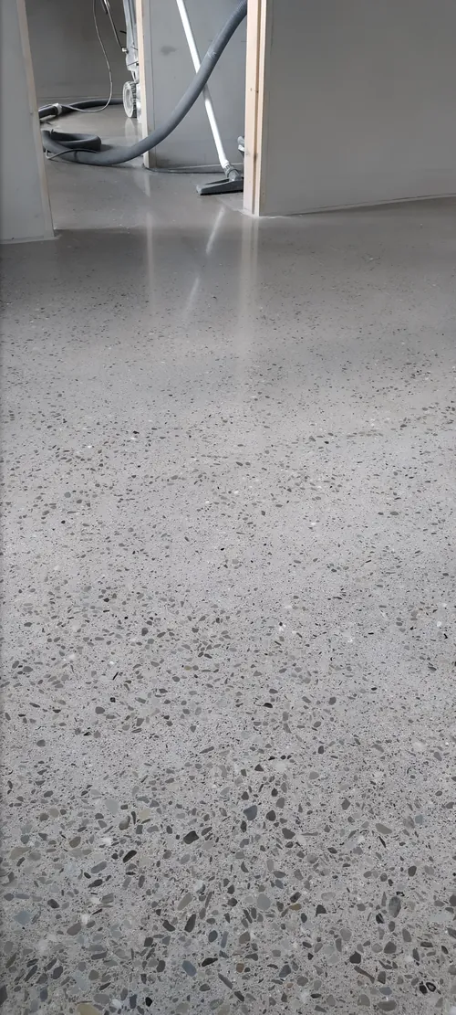Polished concrete floor through a doorway, with the grinder hose in the next room.