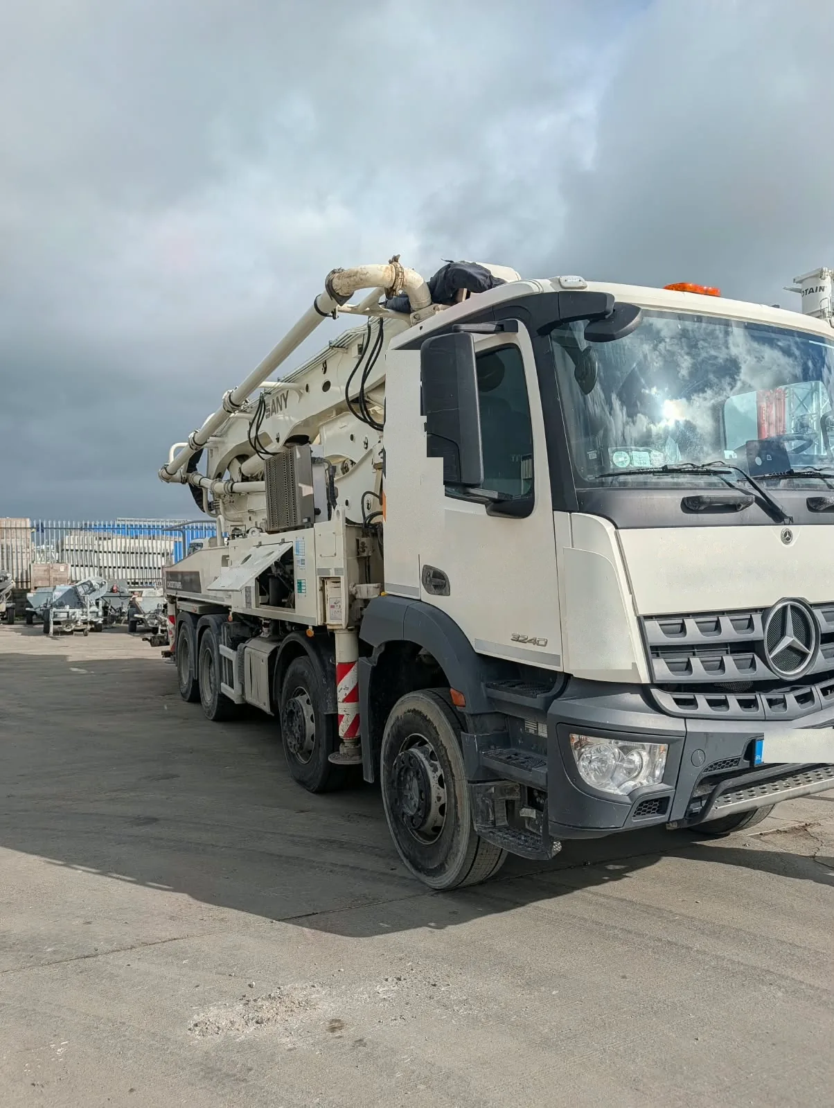 Sany truck-mounted concrete boom pump with the boom folded over the cab, parked in a yard.