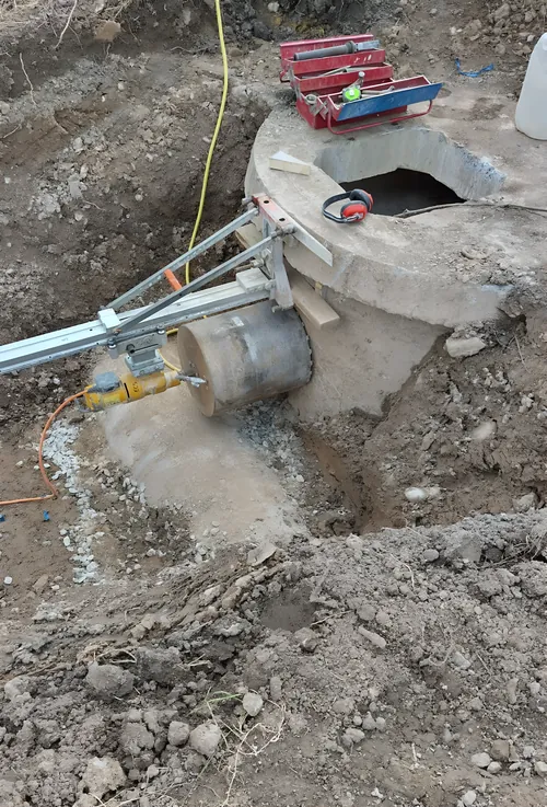 Cutting a pipe entry into a precast concrete manhole ring on a groundworks site.