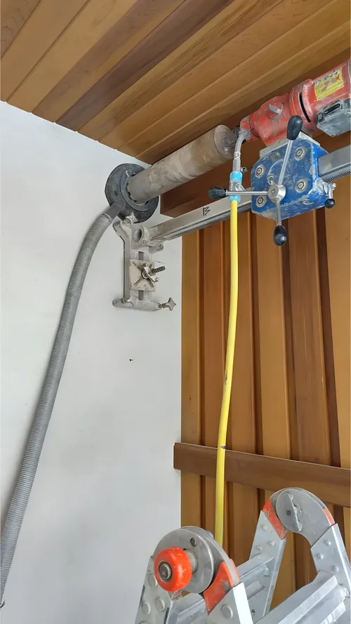 Rig bolted to a finished wall, coring horizontally.