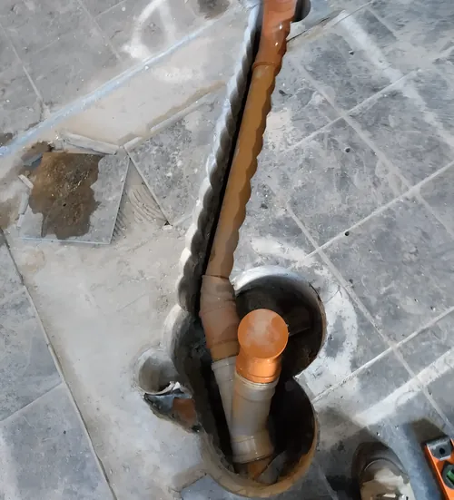 Soil pipe fitted through a hole cored in a tiled ground-floor slab.