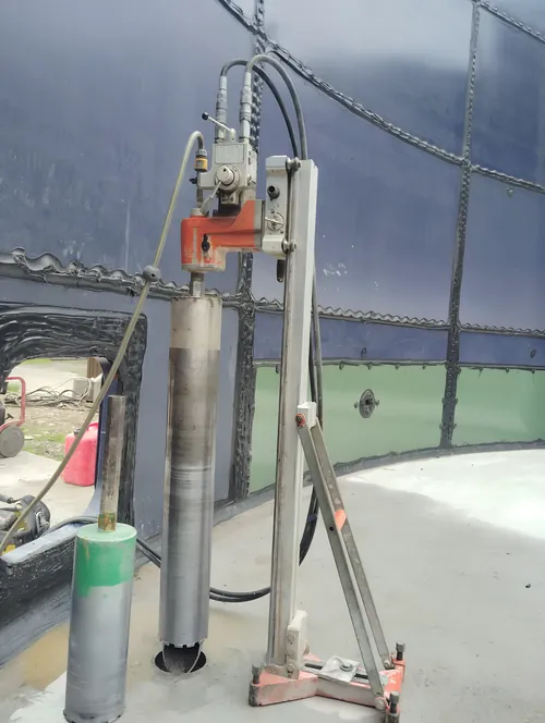 Coring through the concrete base inside a round steel-panel tank.