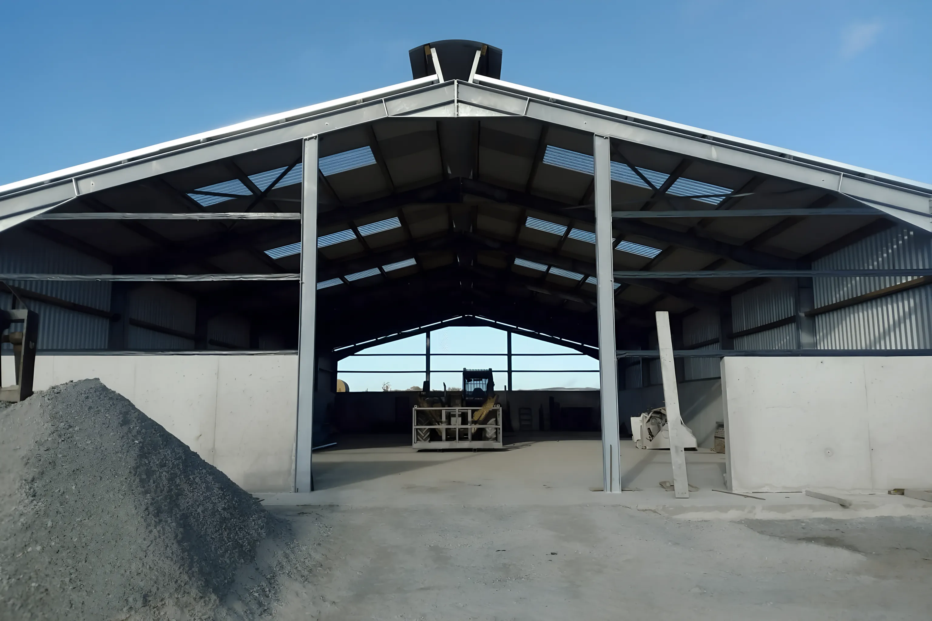Finished steel-framed farm shed with cast concrete walls, open at the gable end.