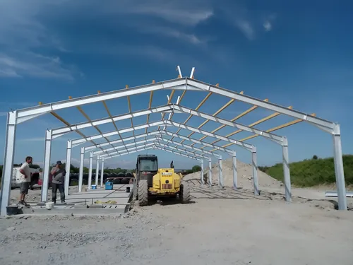 Steel portal frame of a new farm shed going up on a stone base.