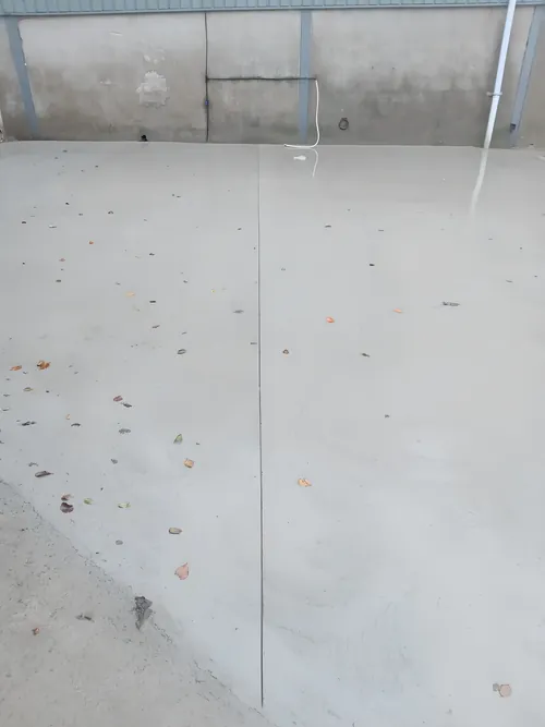 Smooth concrete floor slab with a sawn joint running across it.