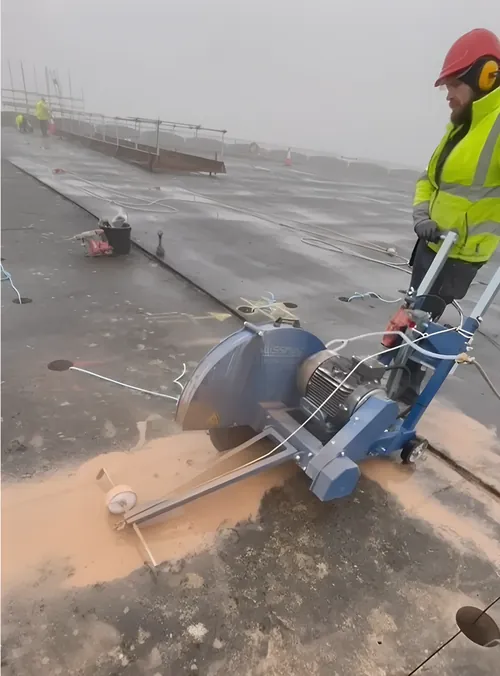 Floor saw cutting a concrete deck, with the slurry spreading from the cut.