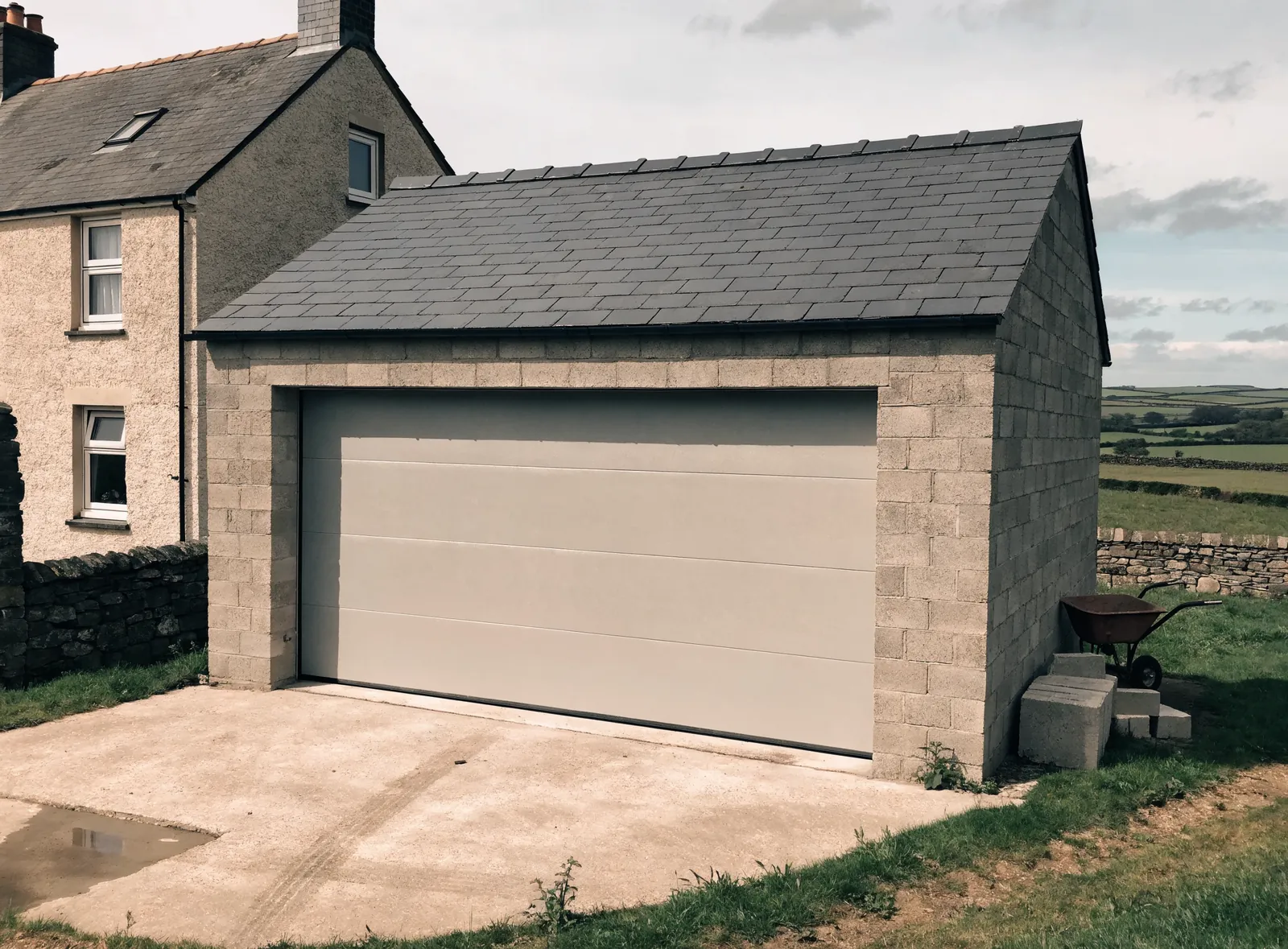 Single-storey garage extension with block walls and a slate roof beside a rendered house.