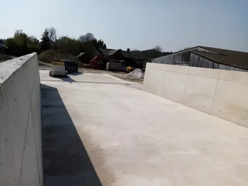 Cast concrete walls either side of a new concrete floor in a farmyard.