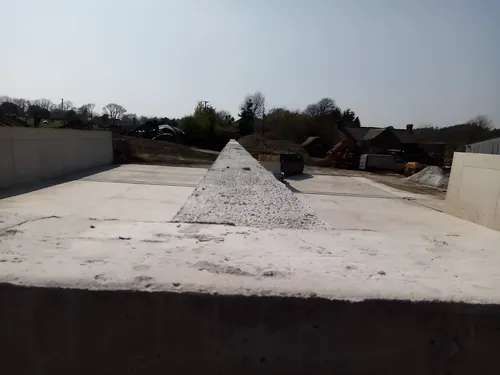 Cast concrete walls around a new slab, with a heap of stone on the floor.