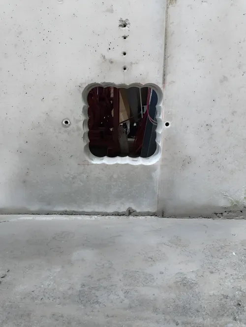 Square opening through a concrete wall, formed by stitch coring with overlapping cores.