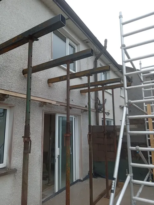 Steel needles through the front wall of a house, each carried on props on both sides.