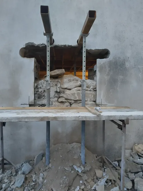 Steel needles through a stone wall, carried on props, with the masonry below being taken out.