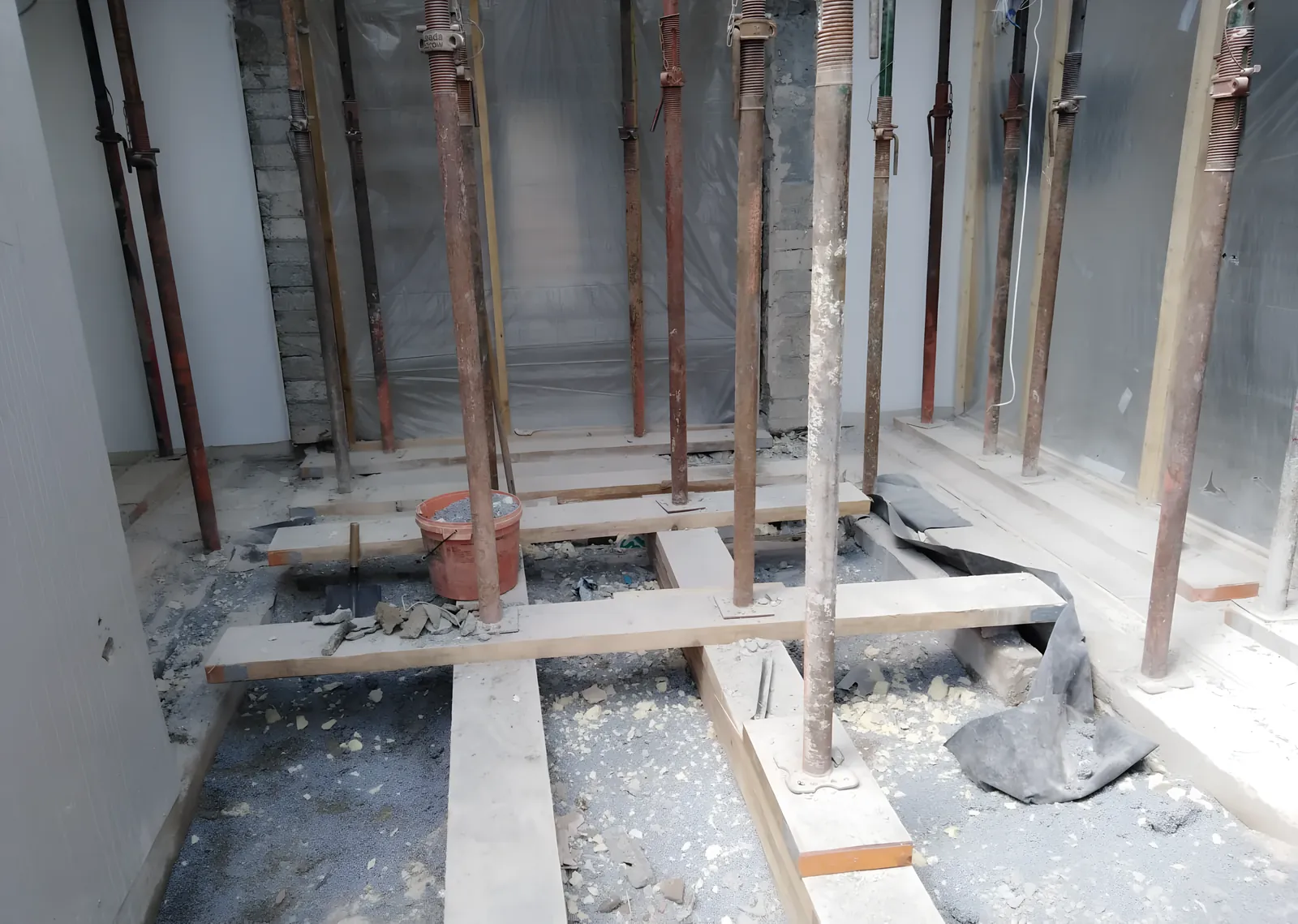 Adjustable props on timber sole plates carrying the floor above during the works.