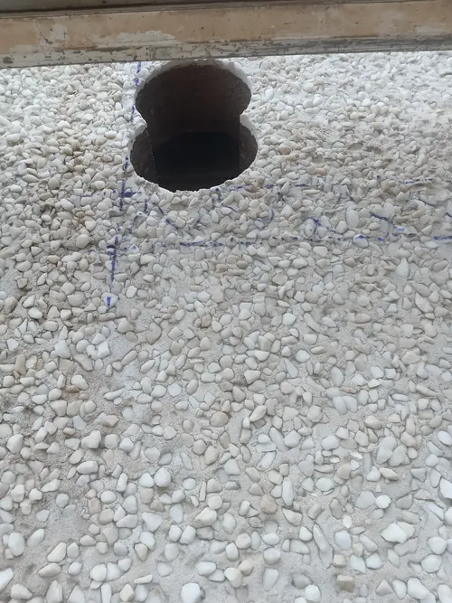 Two overlapping cores through a pebble-dashed wall, with the setting-out marks in pen.