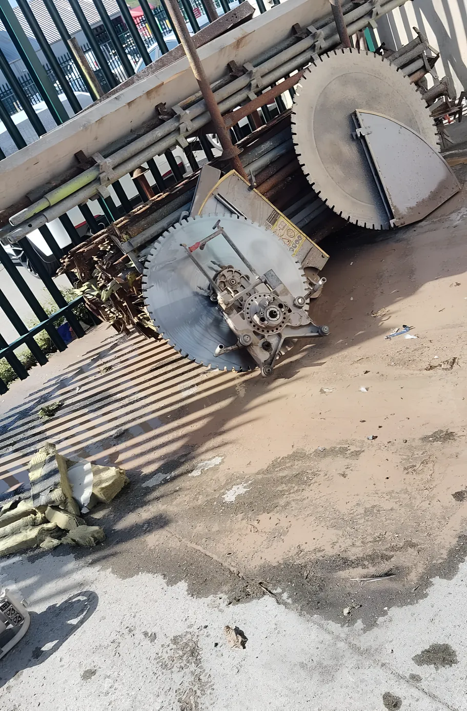Two wall saw heads with their diamond blades, stacked on site beside the saw track.