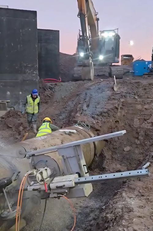 Wire saw set up on a large concrete pipe in an open excavation.